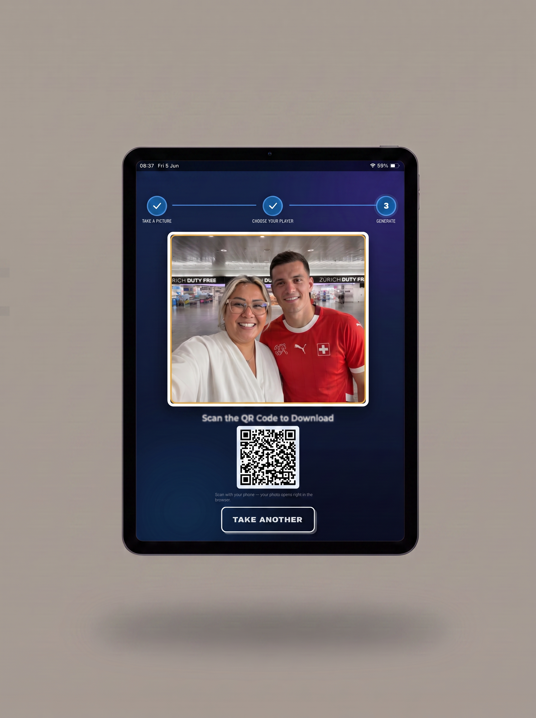 A tablet device centered on a plain taupe background, displaying a blue app interface with a photo of two people, a QR code, and a 'TAKE ANOTHER' button.