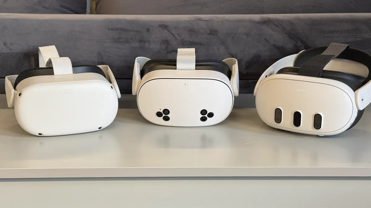 Three white VR headsets on a gray surface with a blurred background